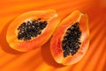 Papaya fruit on tropical orange background with shadows of palm tree. Halved fresh organic Papayas