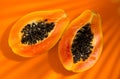 Papaya fruit on tropical orange background with shadows of palm tree. Halved fresh organic Papayas