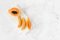 Papaya Half and Slices on White Marble Board