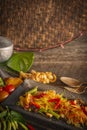 Papaya Salad Som tum Thai on square black plate placed on the wood table there are long bean, palm sugar, fork, spoon, tomato,