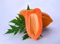 Papaya seedless, cut in half with leaves on a white wooden floor Royalty Free Stock Photo