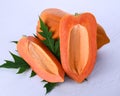 Papaya seedless, cut in half with leaves on a white wooden floor Royalty Free Stock Photo