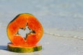 Papaya slice on the sand on water