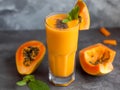 Papaya smoothie in a glass, garnished with mint against dark background. Creamy papaya beverage on rustic wood background. Royalty Free Stock Photo