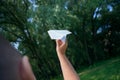 Paper airplane in children hands on greenery background and blue sky in sunny summer day. Concept of summer, childhood, dreaming. Royalty Free Stock Photo