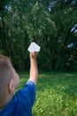 Paper airplane in children hands on greenery background and blue sky in sunny summer day. Concept of summer, childhood, dreaming. Royalty Free Stock Photo