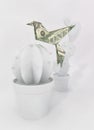 Origami concept. Dollar bill bird on a paper cactus.