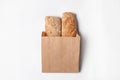 Paper bag with bread loaves on white background, top view. Royalty Free Stock Photo