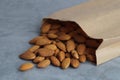 Paper bag with delicious almonds on grey table, closeup