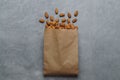 Paper bag with delicious almonds on grey table, top view