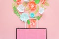 Paper bag of different paper flower on a pink background. Shopping.