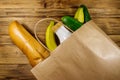 Paper bag with different food on wooden table. Top view. Grocery shopping concept Royalty Free Stock Photo