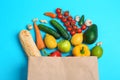 Paper bag with different groceries on blue background, flat lay Royalty Free Stock Photo