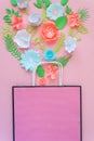 Paper bag of different paper flower on a pink background. Shopping.