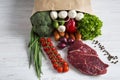 Paper bag of different vegetables and fruits on wooden background. Healthy food. Royalty Free Stock Photo