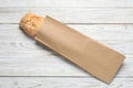 Paper bag with fresh baguette on wooden table, top view Royalty Free Stock Photo