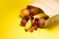 Paper bag with fresh fruits cherry, nectarine, apricots, peaches on a bright yellow background Royalty Free Stock Photo