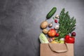 Paper bag with fresh vegetables and apples on dark background, flat lay. Royalty Free Stock Photo