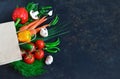 Paper bag with fresh vegetables on a dark background: tomato, zucchini, onion, lettuce, dill, pepper, cucumber, garlic Royalty Free Stock Photo