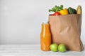 Paper bag with fresh vegetables and other products on white wooden table against light background Royalty Free Stock Photo