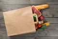 Paper bag full of different food on wooden background Royalty Free Stock Photo