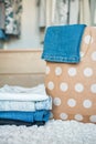 A paper bag with painted circles in which jeans lie, next to a stack of jeans of different colors. In the background is a wardrobe Royalty Free Stock Photo