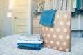 A paper bag with painted circles in which jeans lie, next to a stack of jeans of different colors. In the background is a wardrobe Royalty Free Stock Photo