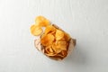 Paper bag of potato chips on white wooden background, space for text Royalty Free Stock Photo