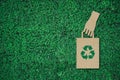 Paper bag with recycle sign in hand, paper cut on green grass background with copy space , green energy iconic symbol, save energy Royalty Free Stock Photo