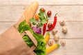 Paper bag with various fresh vegetables and baguette on wooden background Royalty Free Stock Photo