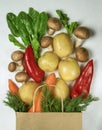 paper bag with vegetables: potatoes, mushrooms, red pepper, carrots, spinach, dill, top view. Healthy food
