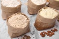 Paper bags with different types of flour and ingredients on white marble table Royalty Free Stock Photo