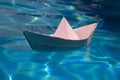 Paper boat on blue water background. Paper boat sailing on blue water surface. Concept of tourism, travel dreams Royalty Free Stock Photo