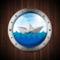 Paper boat in the blue waves of the sea seen through the porthole Royalty Free Stock Photo