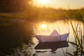 A paper boat floats on the water at dawn.