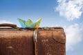 Paper boat folded from a map on an old vintage suitcase against a blue sky with white clouds, wanderlust, cruise and travel Royalty Free Stock Photo