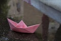 Paper boat, Origami ship, floats in a puddle formed by the pouring rain. Photo idea: floods, autumn or winter weather