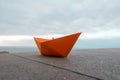 Paper orange boat on a railing with sky and ocean background Royalty Free Stock Photo