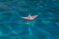 Paper boat sailing on blue water surface. Paper boat into water. Concept of tourism, travel dreams vacation holiday Royalty Free Stock Photo