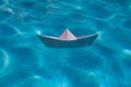 Paper boat sailing on water causing waves and ripples. Paper boat into water. Concept of tourism, travel dreams vacation Royalty Free Stock Photo