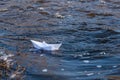 A paper boat on a turbulent stream of water struggles with the flow. Small paper boat is flowing along river Royalty Free Stock Photo