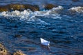 A paper boat on a turbulent stream of water struggles with the flow. Small paper boat is flowing along river Royalty Free Stock Photo
