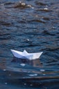 A paper boat on a turbulent stream of water struggles with the flow. Small paper boat is flowing along river Royalty Free Stock Photo