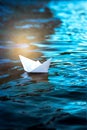 Paper boat in the water, white origami ship floats on the waves, vertical frame Royalty Free Stock Photo