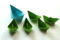Origami paper ships in light blue and green colors.