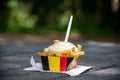 Paper box in colors of Belgian flag with fried potato frit chips and mayonnaise sauÃÂe