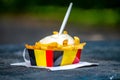 Paper box in colors of Belgian flag with fried potato frit chips and mayonnaise sauÃÂe