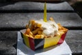 Paper box in colors of Belgian flag with fried potato frit chips and mayonnaise sauÃÂe