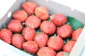 Paper box with red strawberry for sale in the fruit and vegetable market. Close up. Tasty seasonal fruit, fresh and heathy.