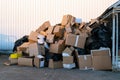 Paper boxes next to a garbage bin. Stack of paper waste outdoor in the city. Paper recycling, nobody